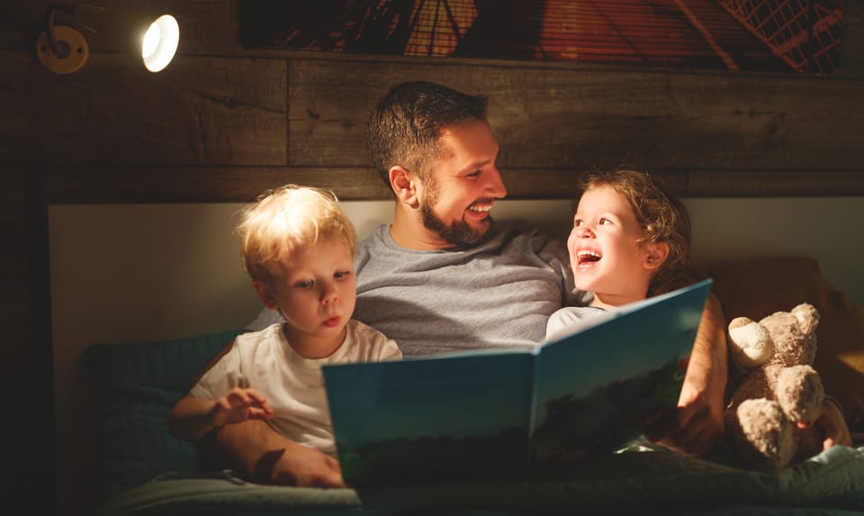 Un hombre lee un cuento con un niño y una niña.